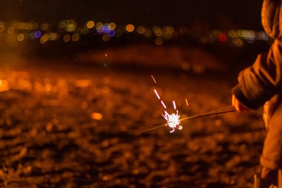 Low angle view of hand holding sparkler at night