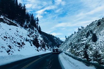 Road amidst trees against sky during winter