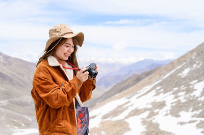 Woman wearing hat standing against mountain during winter