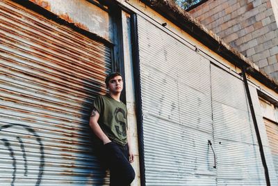 Thoughtful teenage boy standing against closed shutter