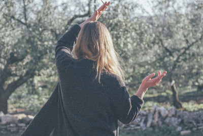 Rear view of woman standing against trees