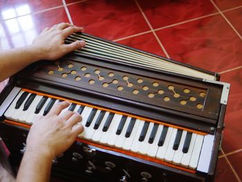 Cropped image man playing harmonium on tiled floor