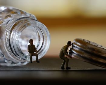 Close-up of figurines with bottle on table