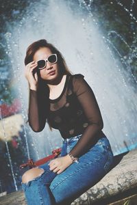 Young woman wearing sunglasses sitting outdoors