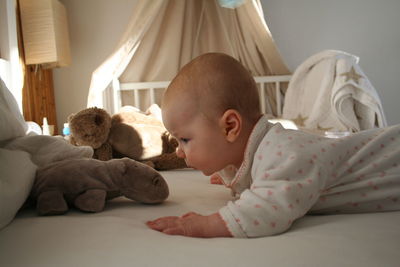 Side view of baby looking at toy on bed at home