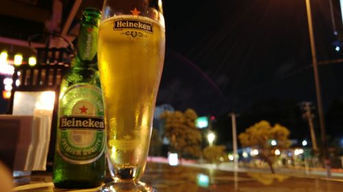 Glass of beer bottles on bar counter at night