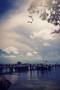 Pier on sea against cloudy sky