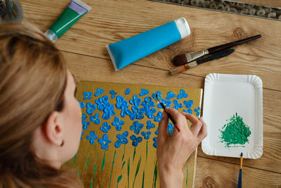 Woman artist painting picture at home with acrylic paints, spatula. adult hobby and free time person