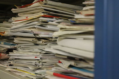 Close-up of stack newspapers on shelf