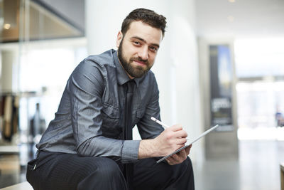 Portrait of young man using mobile phone in office