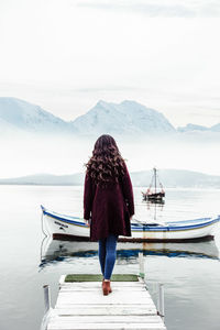 Rear view of woman standing on lake against mountain