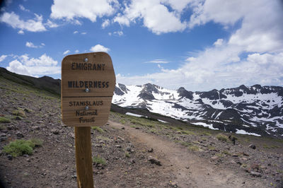 Information sign on road by mountain against sky