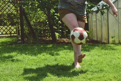 Low section of woman playing football on field