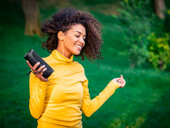 Happy young woman enjoying music in park