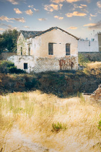 Old house on field against sky