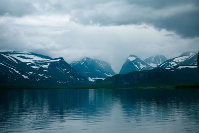 Scenic view of lake by snowcapped mountains against sky
