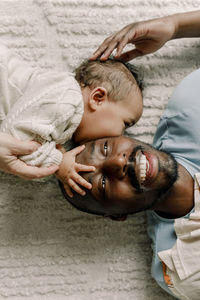 Male toddler kissing father lying on blanket at home