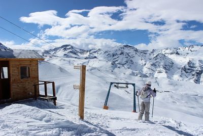 Woman walking on snowcapped mountains against sky