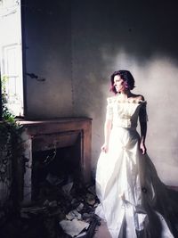 Portrait of young woman standing against abandoned building