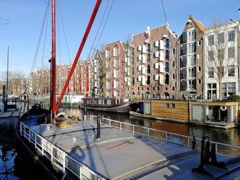 Sailboats moored on canal by buildings against sky in city