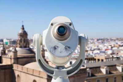 Close-up of coin operated binoculars against cityscape