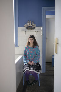 Portrait of a young woman sitting on door