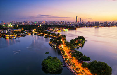 High angle view of illuminated city by river at night