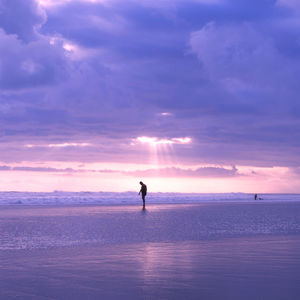 Silhouette man standing at beach against sky during sunset