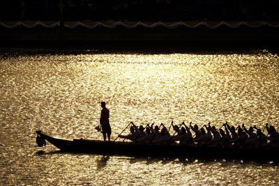 Silhouette people on boat in water