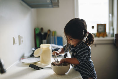 Rear view of girl having food at home