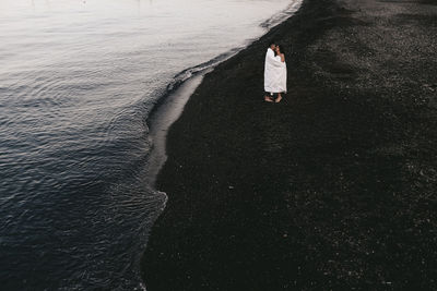 A couple in love spend the night at the sea, kissing and hugging on the beach covered with a blanket