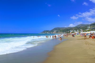 People on beach against blue sky