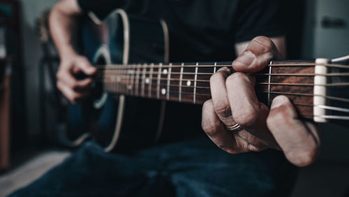 Midsection of man playing guitar