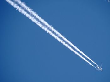 Low angle view of airplane flying against clear blue sky