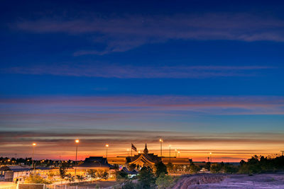 Illuminated buildings against sky at sunset