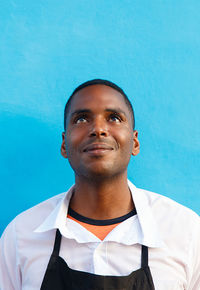 Smiling young man looking away against blue wall