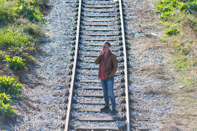 Single man standing and smoking on railroad tracks