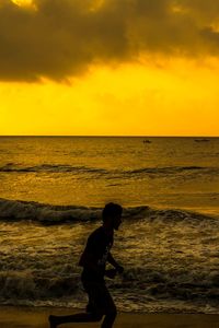 Man on beach against sky during sunset