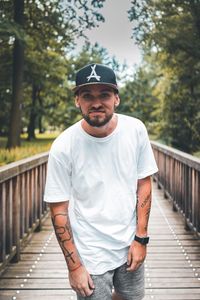 Portrait of young man standing on footbridge