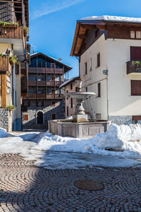 Snow covered buildings against blue sky