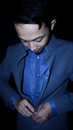 Close-up of young man looking away over black background