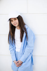 Portrait of young woman standing against wall