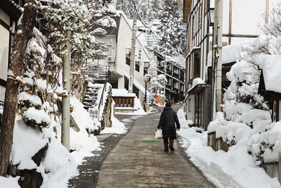 Rear view of man walking on snow covered street