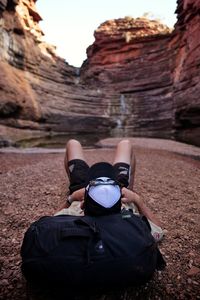 Rear view of man lying on desert against rock formations