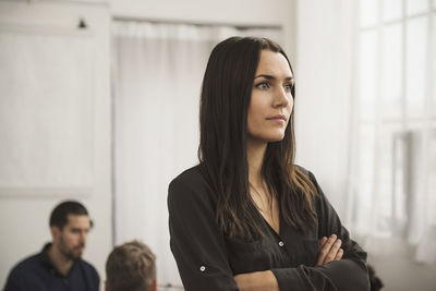 Thoughtful businesswoman with arms crossed in office