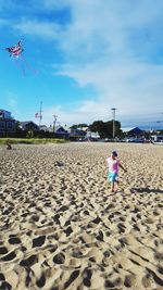 Child playing on beach against sky