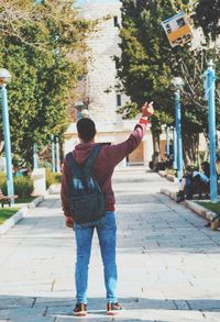 A young man wears a bag and throws the book in the air