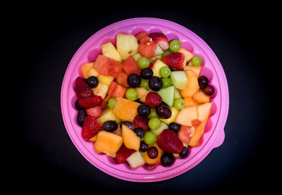 Close-up of fruits in plate against black background