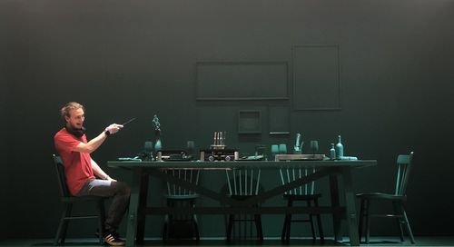 Man laughing and gesturing while sitting on chair at dining table in darkroom