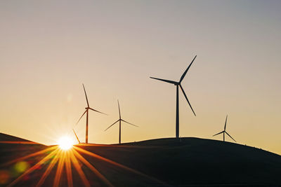Wind power turbines on the hill in a sunset or sunrise light, sustainable energy